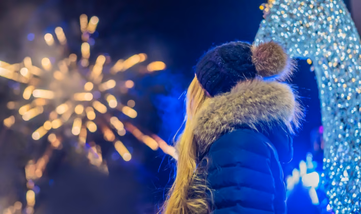 Colaboradora observando los fuegos artificiales en la fiesta de fin de año nocturna de la empresa