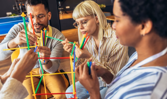 Colaboradores armando una estructura con piezas de colores en un reto de construcción de team building