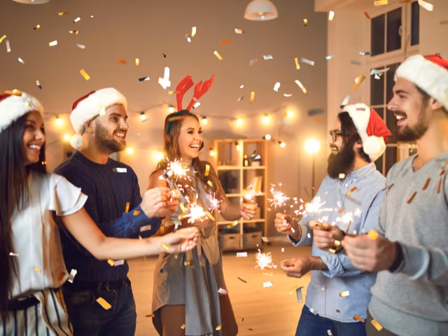 Colaboradores celebrando con luces de bengala y confeti en la fiesta de fin de año de la empresa