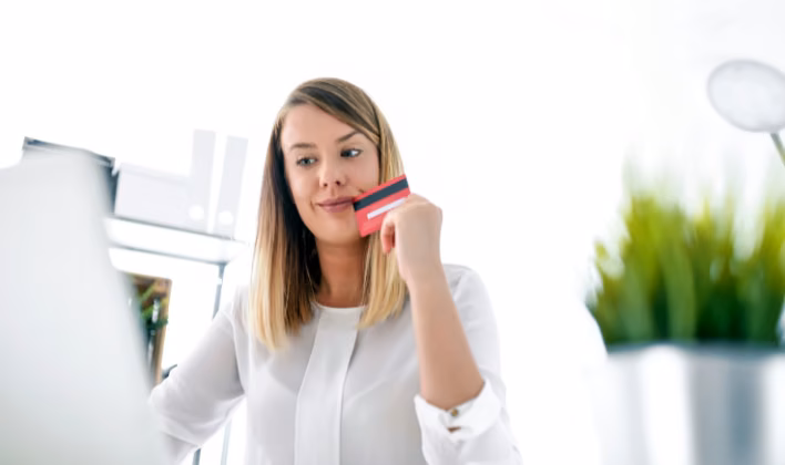 Mujer con tarjeta en mano comparando la cotización de un evento corporativo antes de pagar