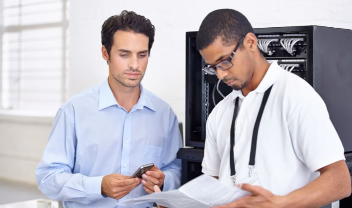 Técnico y coordinador revisando el equipo audiovisual antes de un evento corporativo