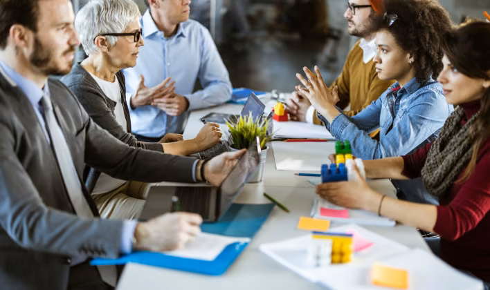 Equipo debatiendo con bloques de construcción y notas adhesivas en una dinámica de team building con objetivo
