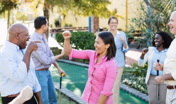 Colaboradores celebrando durante una partida de minigolf en una integración empresarial al aire libre