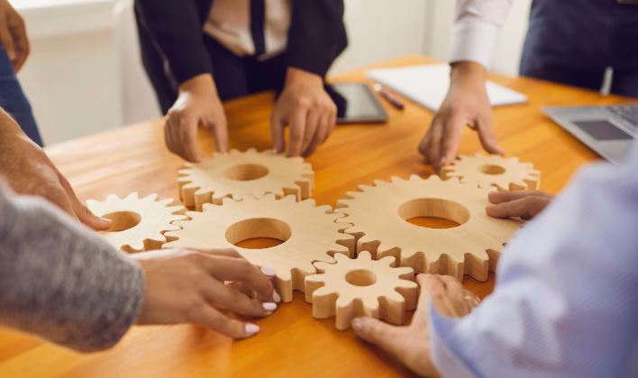 Equipo armando piezas de engranaje de madera en una dinámica de team building sobre cooperación