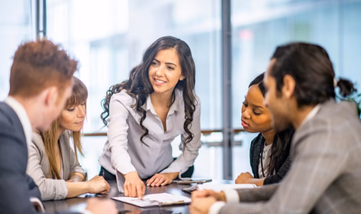 Facilitadora guiando una dinámica de team building con un subgrupo de colaboradores en la mesa