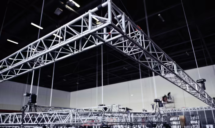 Estructura truss de aluminio armada en pórtico, con los tubos unidos por diagonales en triángulos y más tramos apilados en el piso