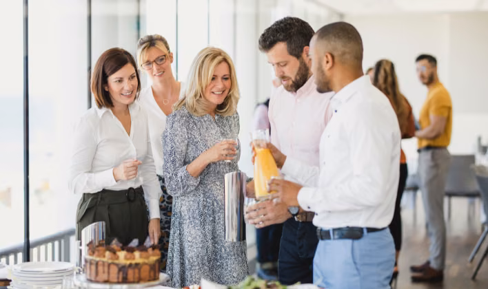 Colaboradores celebrando con copas y postres en una fiesta de fin de año en la oficina