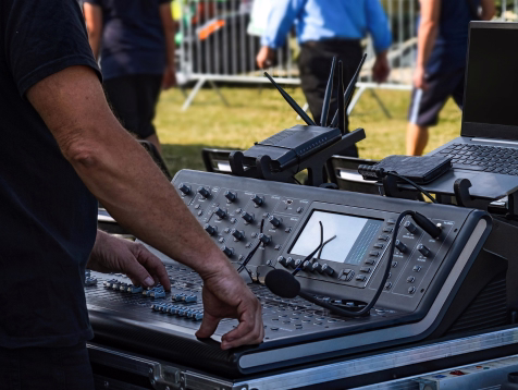 Técnico de sonido operando la consola de mezcla durante un evento empresarial al aire libre