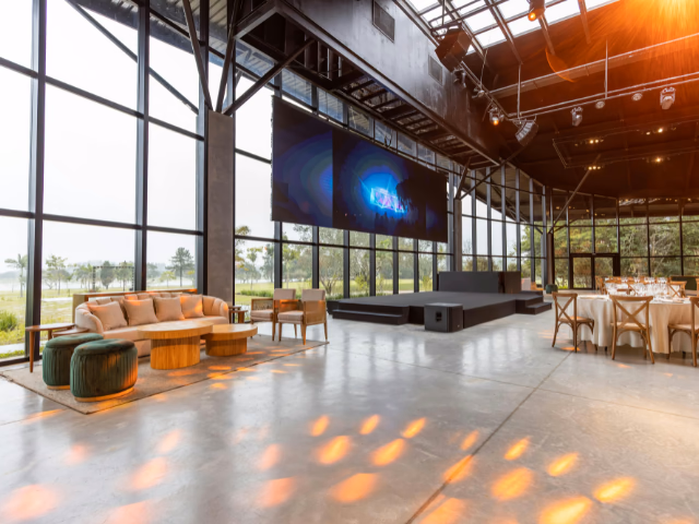Pantalla LED de gran formato sobre la tarima de un salón de eventos empresarial, vista desde el fondo del espacio
