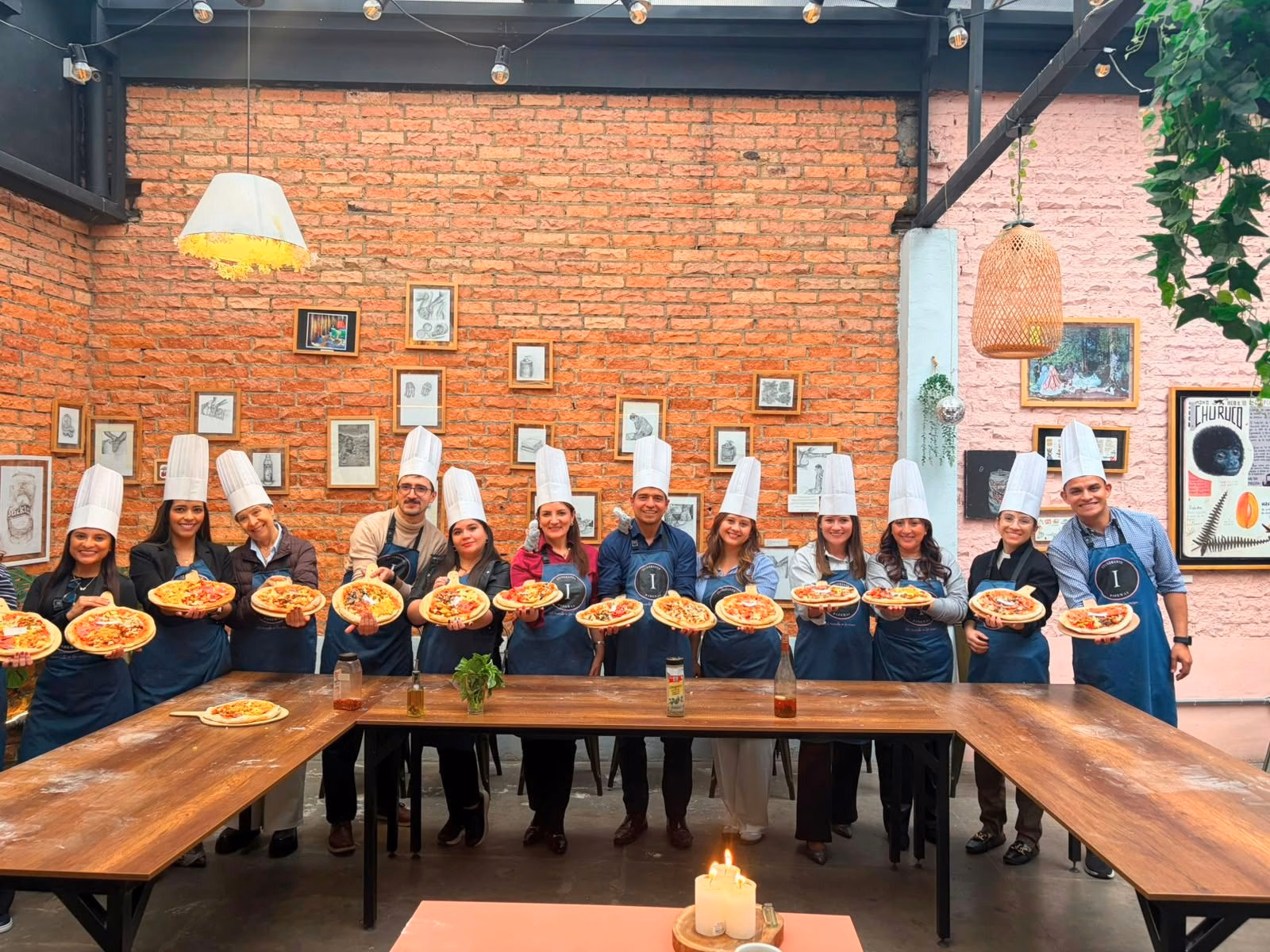 Equipo corporativo sosteniendo pizzas artesanales en un taller de team building gastronómico en Bogotá