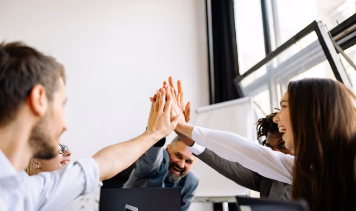 Colaboradores chocando las manos en el cierre colectivo de un team building para equipos grandes