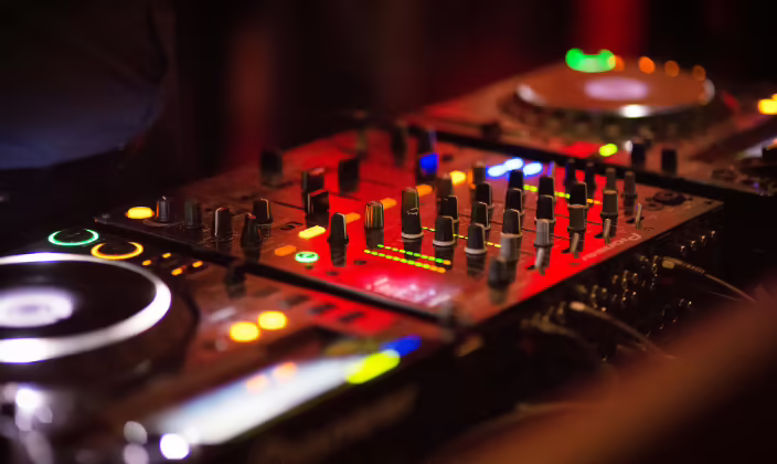 Consola de sonido iluminada, con sus perillas y faders, operada durante un evento empresarial nocturno