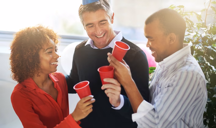 Colaboradores brindando con vasos rojos durante la fiesta de fin de año empresarial
