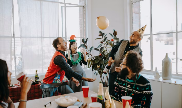 Colaboradores con gorros y accesorios temáticos celebrando la fiesta de fin de año empresarial