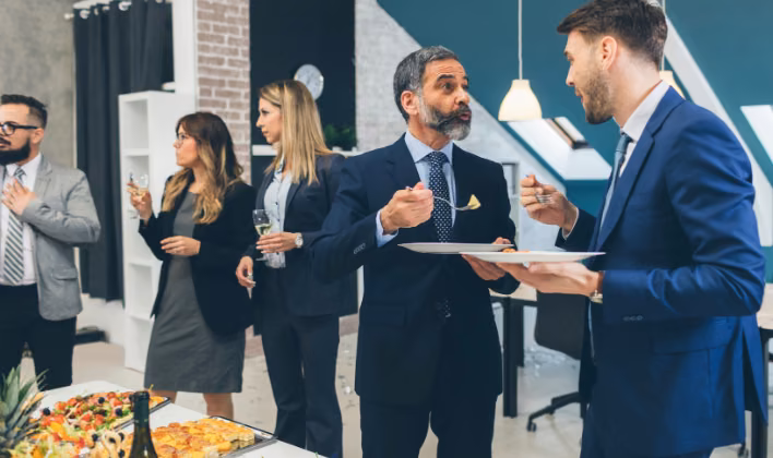Directivos conversando y compartiendo un aperitivo en un evento de networking corporativo